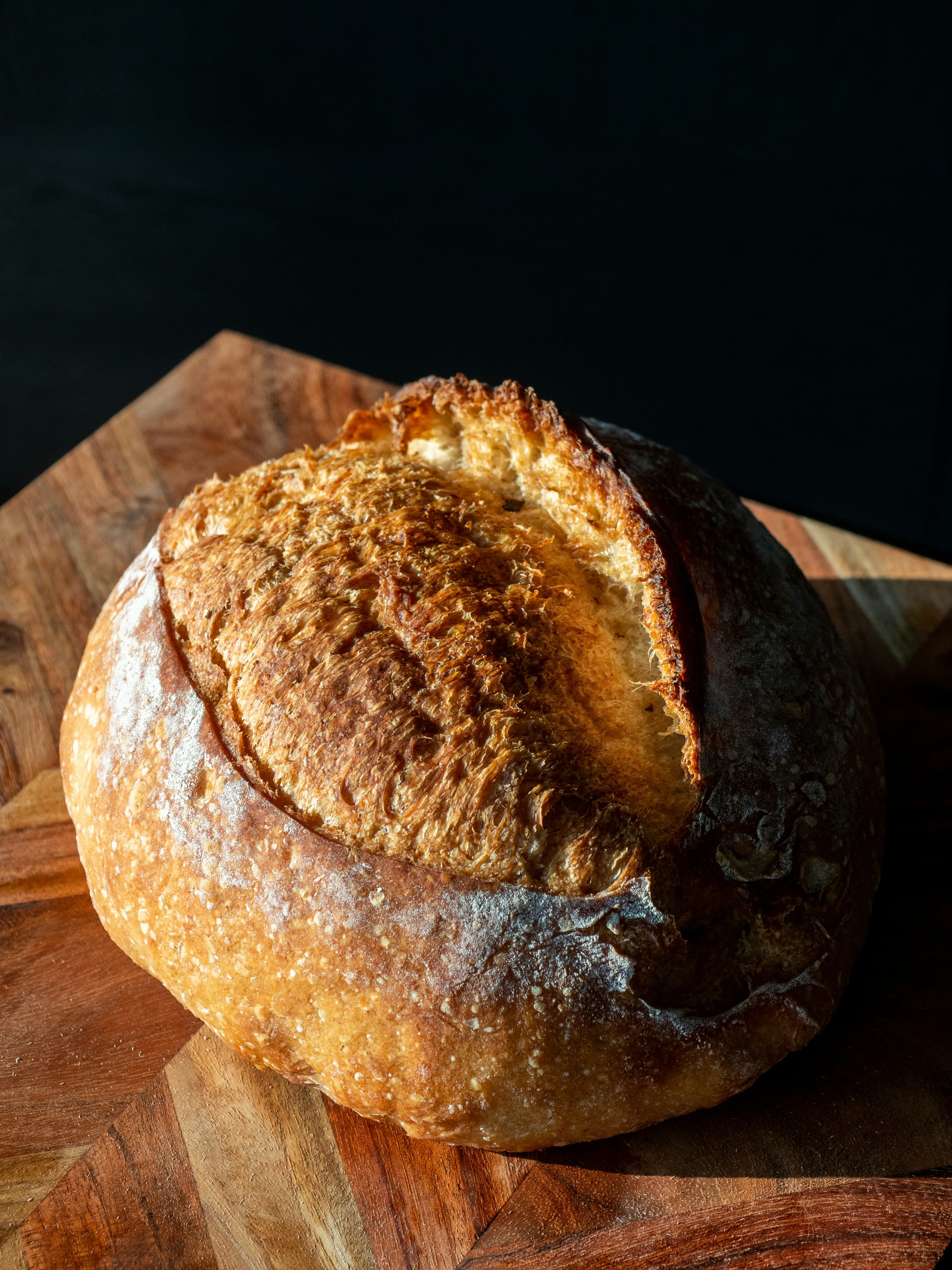 A golden round sourdough loaf on a wooden board